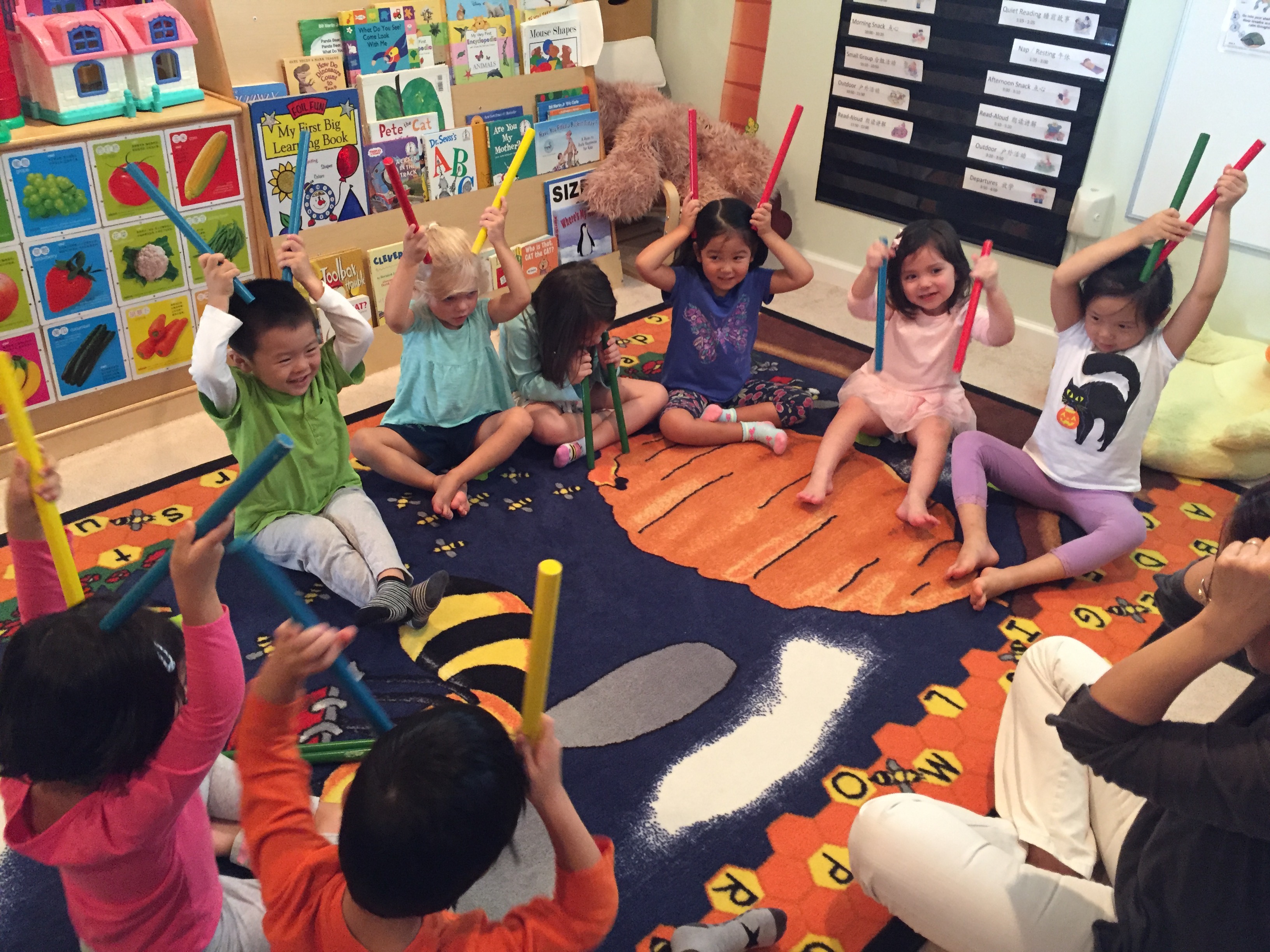 A group of diverse children play with colorful sticks together during circle time at A&D Stars.