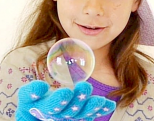 A young girl wearing a glove shows how to gently hold a bubble without popping it.