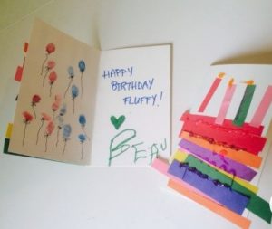 Two homemade birthday cards decorated with paper candles and thumbprint balloons.