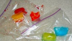 Ice cubes dyed with food coloring beginning to melt in two plastic bags