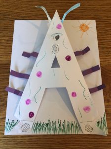 The letter "A" made from paper and decorated like a bug with legs and antennae