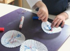 A child drawing on white cupcake liners