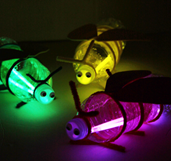 Three colored lightning bug flashlights made from water bottles and glow sticks