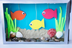 A play aquarium made with a shoe box, paper, pipe cleaners, small stones, and shells