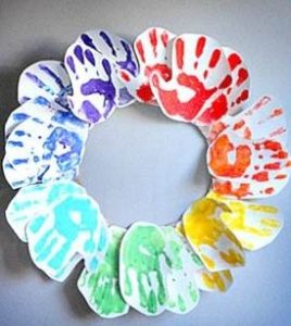 A wreath made from handprints on paper in the colors of the rainbow.