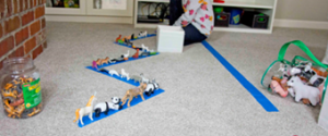 Toy animals lined up on blue painter's tape on carpet