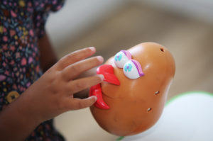A young child putting the features on a potato head toy