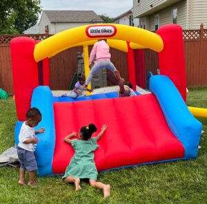 young children playing outside on inflatable slide