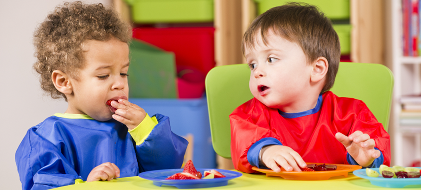 Two infants eating in a preschool classroom